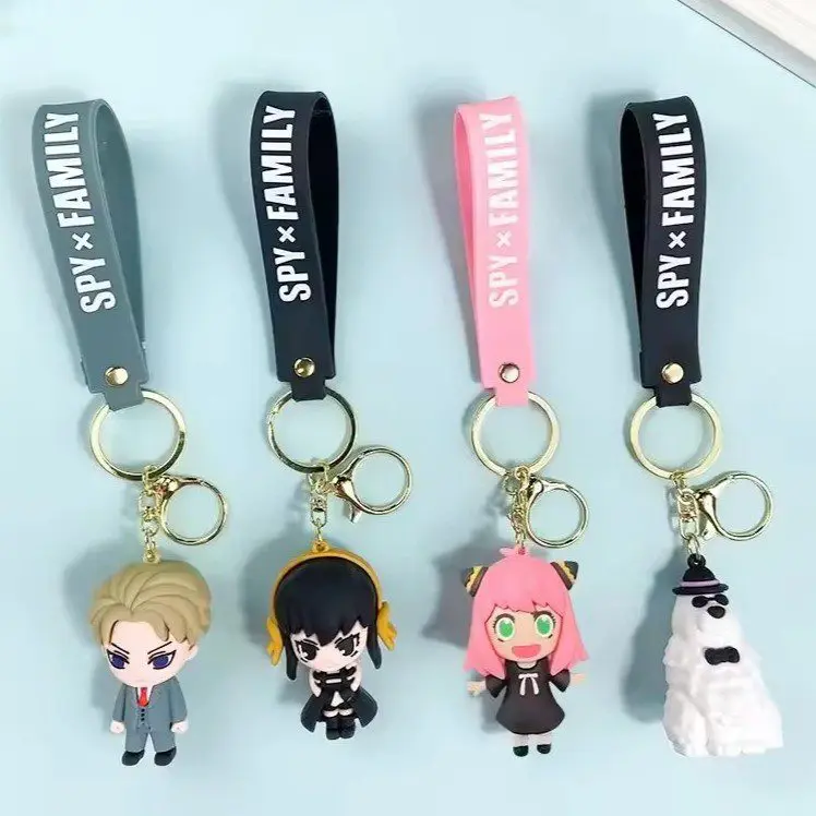 Four SPY x FAMILY character keychains hanging from colored straps: Loid (blonde hair) on gray strap, Yor (black hair) on dark strap, Anya (pink hair) on pink strap, and Olaf the snowman on black strap.